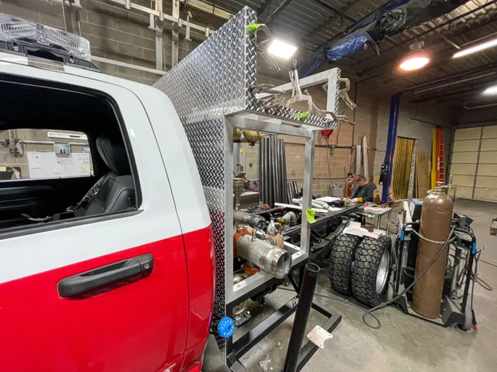 Exterior view of small fire truck showing cab, body compartments, and wheel/tire area.